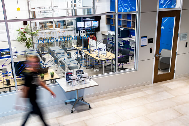 A student walks past the exterior view of the AI Lab; located in the Robert W. Palster Free Enterprise Center.