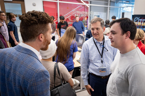 Three attendees converse inside the CUW AI & Quantum Innovation Lab while others engage with displays and equipment during the November 5, 2025 pitch event.