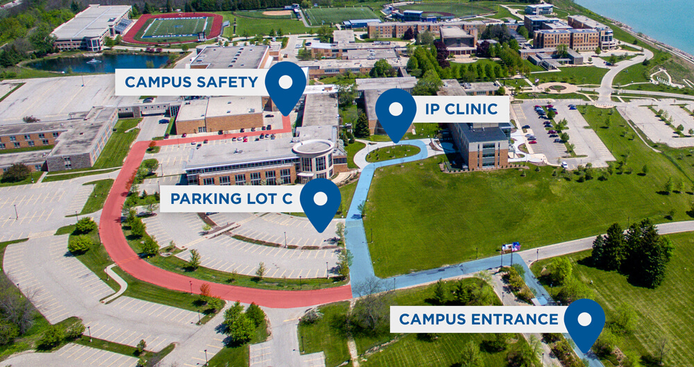 Aerial campus map highlighting the campus entrance, Parking Lot C, campus safety building, and IP Clinic with marked driving routes.