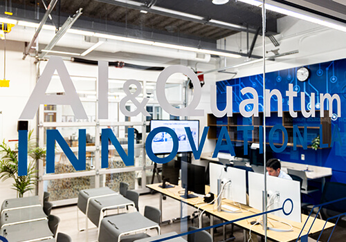 Two students collaborating at a whiteboard in a hallway.