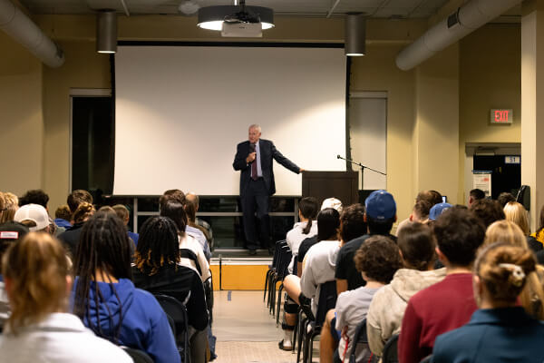 Tom Barrett stands at a podium on stage, addressing a large audience at the Concordia National Security and Space Center’s “Luxembourg in Space” event.
