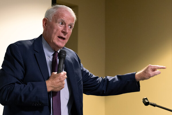 Tom Barrett, wearing a dark blue suit and light blue shirt, speaks at a microphone with his right arm extended during the Concordia National Security and Space Center's 'Luxembourg in Space' event.