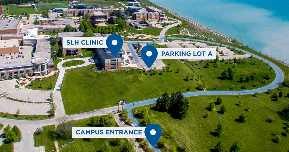 Aerial campus map highlighting the campus entrance, Parking Lot A, the Robert Plaster building, and SLH Clinic with marked driving routes.